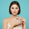 Woman holding skincare products against a teal background