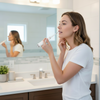 Woman using a plaque remover in a bathroom.