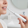 Person using a white dental tool on their mouth with a blurred background