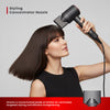 Woman using a hair dryer with a styling concentrator nozzle on a gray background