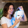Woman holding a white LED face mask with blue light, IGIA brand visible