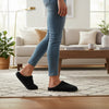 Person wearing black slippers in a living room setting